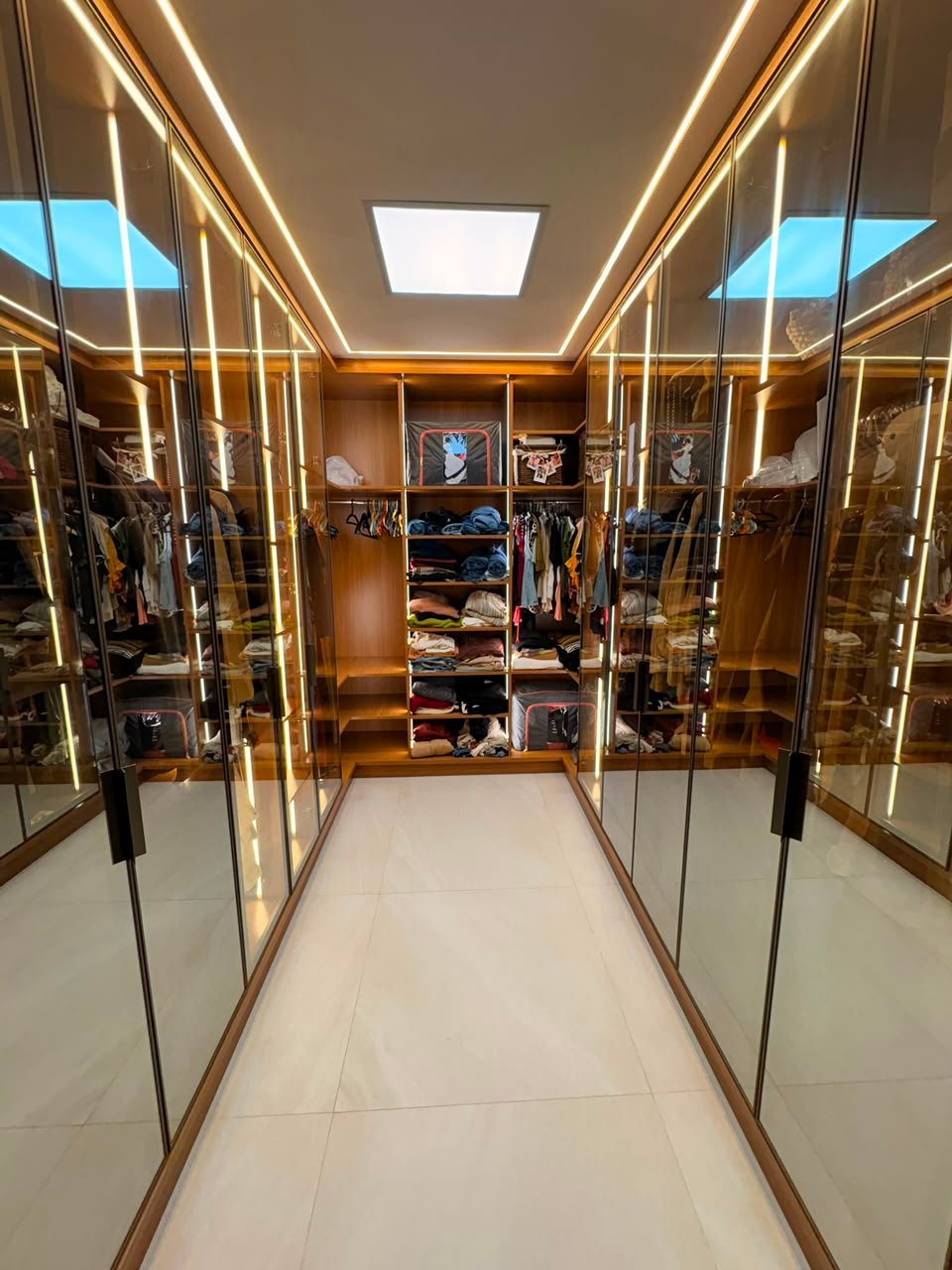 Corredor de closet planejado com portas espelhadas e iluminação em LED