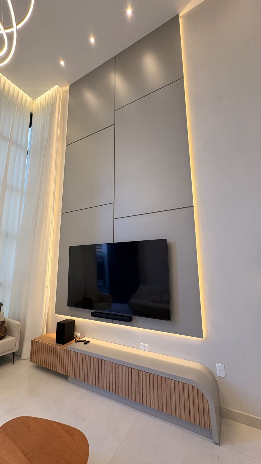 Painel de TV planejado com iluminação em LED dourado e rack ripado